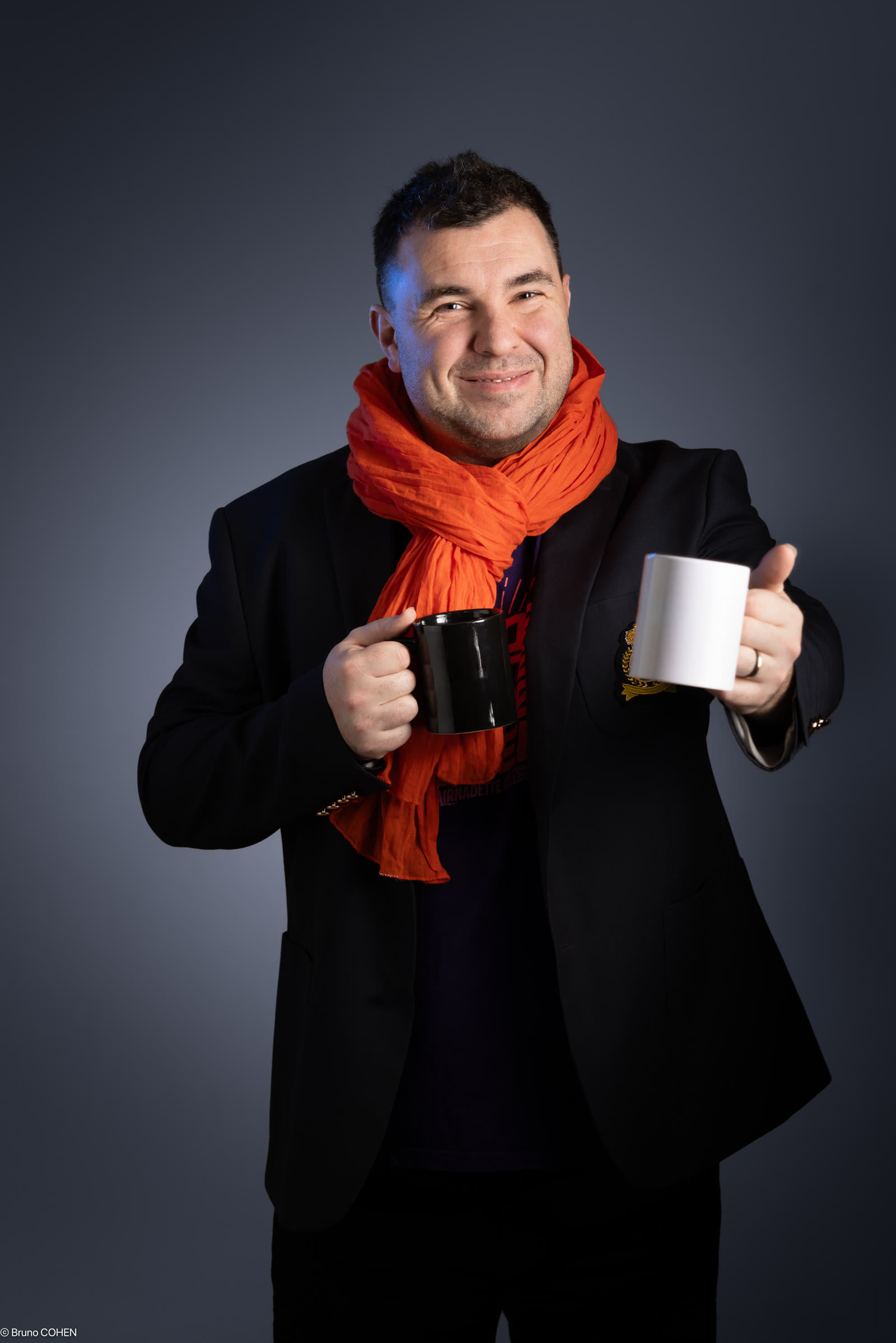 Cyril Noury tendant une tasse de café, deux mugs en main